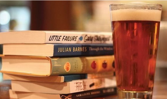 Stack of paperback books with a full beer in glass next to books