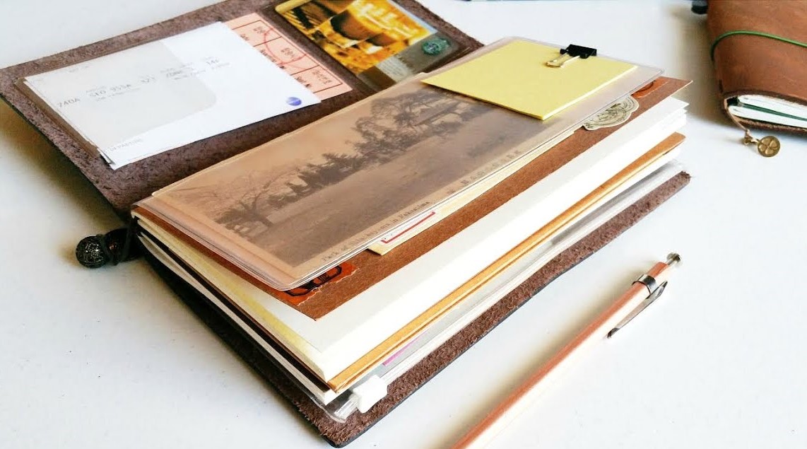 Open notebook with blank pages on a wooden desk with a fountain pen. 