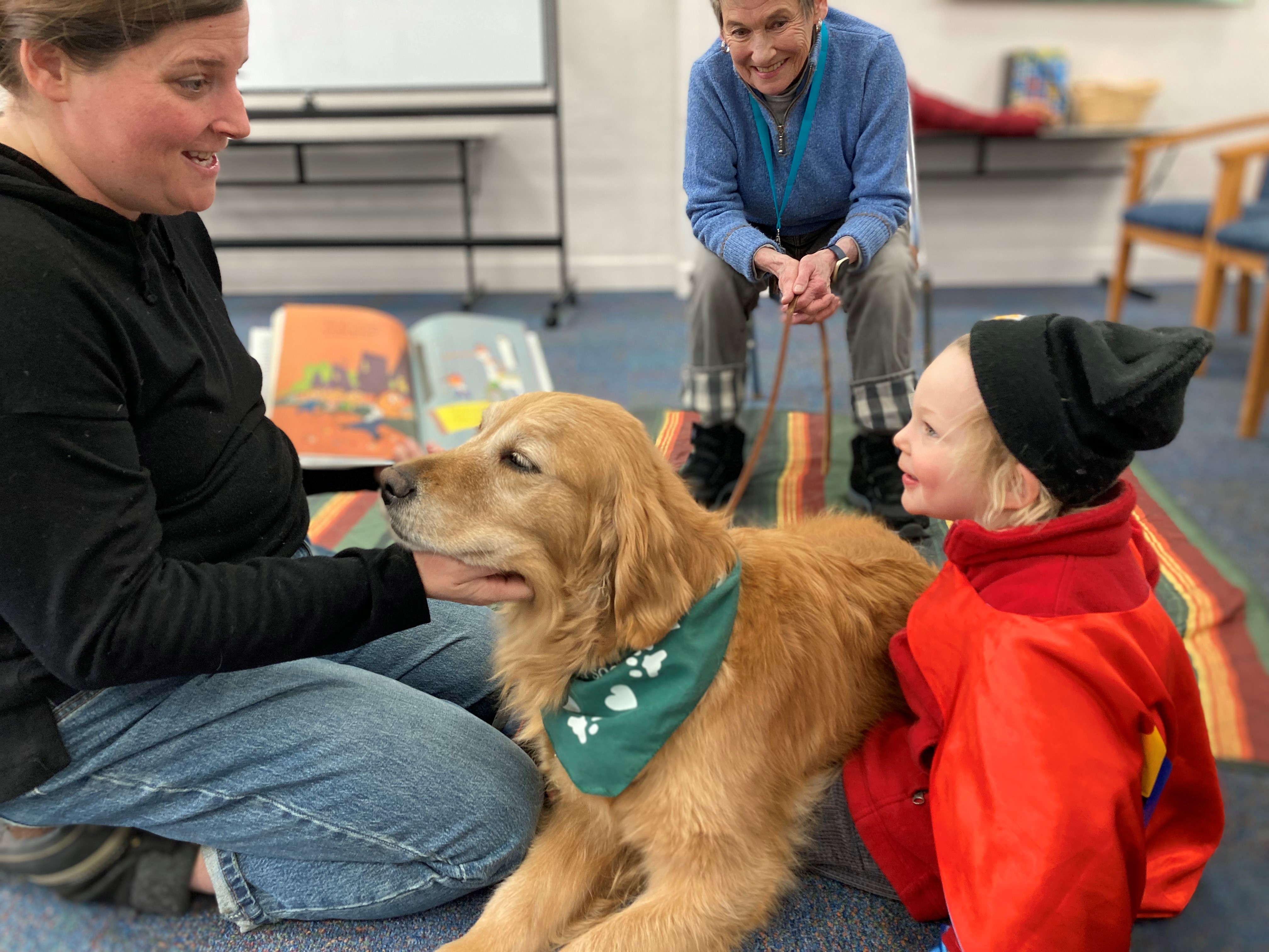 Smiling mother and son reading with Pet partner team