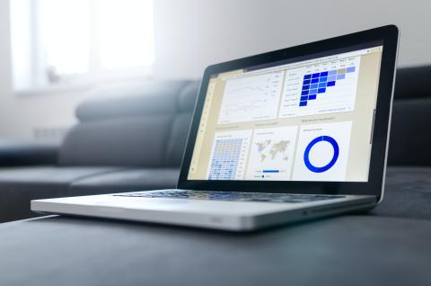 Laptop with screen open featuring a spreadsheet with graphs. 