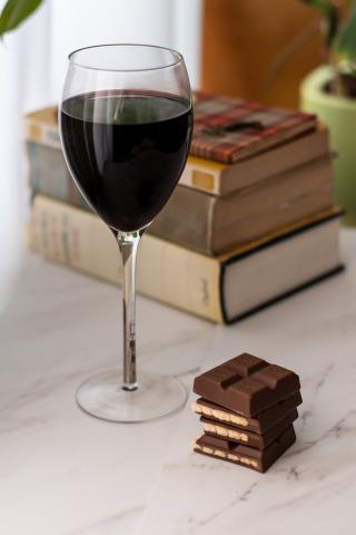 Glass of wine in front of stack of hardback books